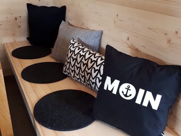 A wooden bench with three black circular mats and three pillows with different patterns and designs. - Rent a bungalow, 300 mtr to the beach, private ground, 4 pers. (Ostseeferiendorf Zierow)