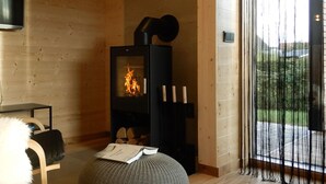A cozy room with a fireplace, a comfortable chair, and a television. - Rent a bungalow, 300 mtr to the beach, private ground, 4 pers. (Ostseeferiendorf Zierow)