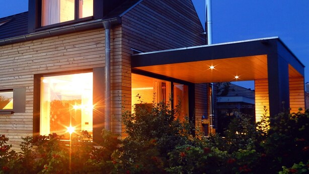 A modern house with a large glass window, a chimney, and a covered outdoor area. - Rent a bungalow, 300 mtr to the beach, private ground, 4 pers. (Ostseeferiendorf Zierow)