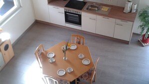 Une cuisine compacte avec des meubles blancs, une cuisinière et une table à manger pour quatre personnes.