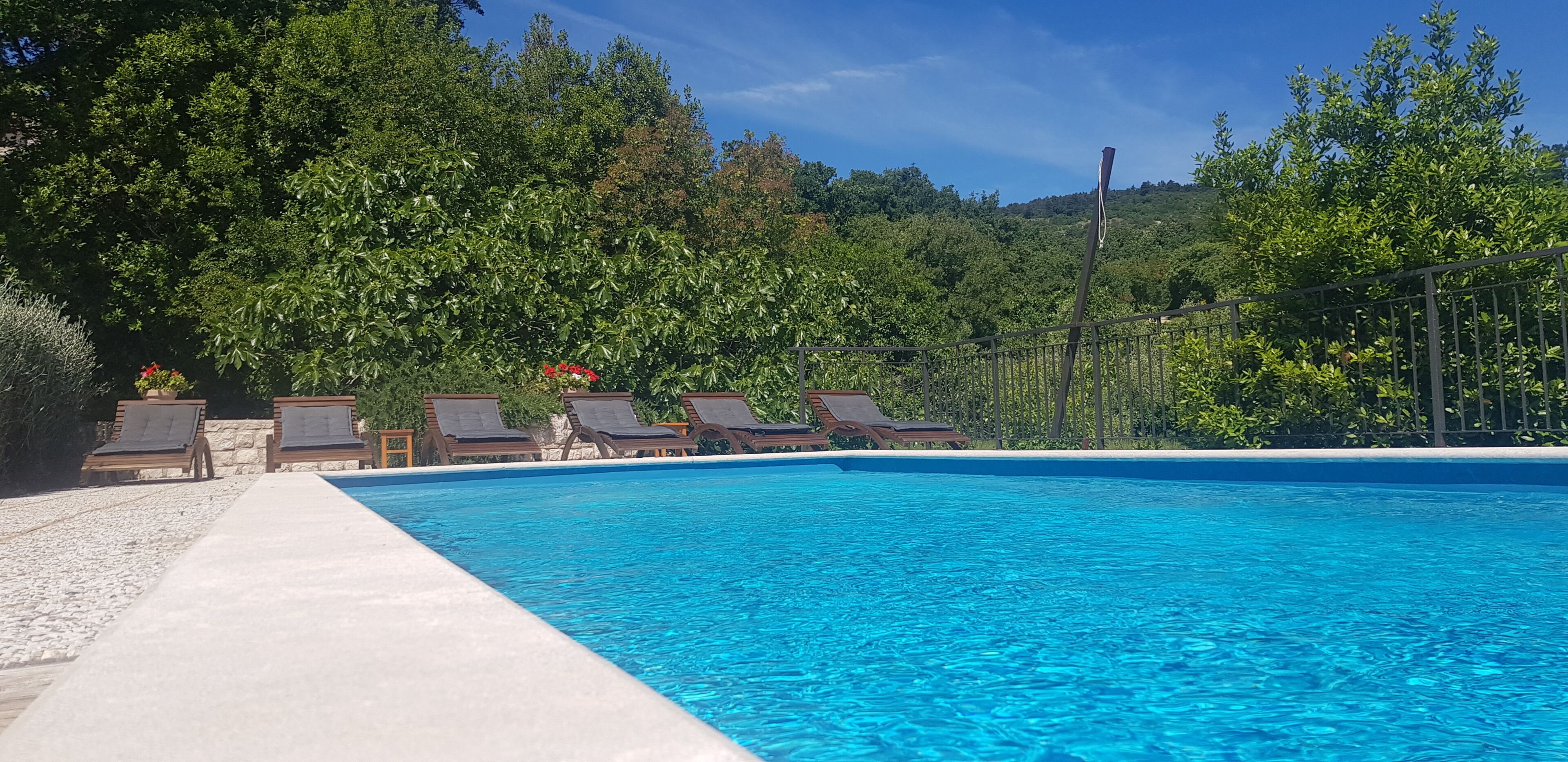 Ein Schwimmbecken mit Liegestühlen und einem Kiesweg.