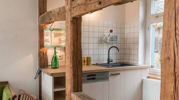 Una cocina con vigas de madera, salpicadero de azulejos, lavavajillas y ventana con vistas.