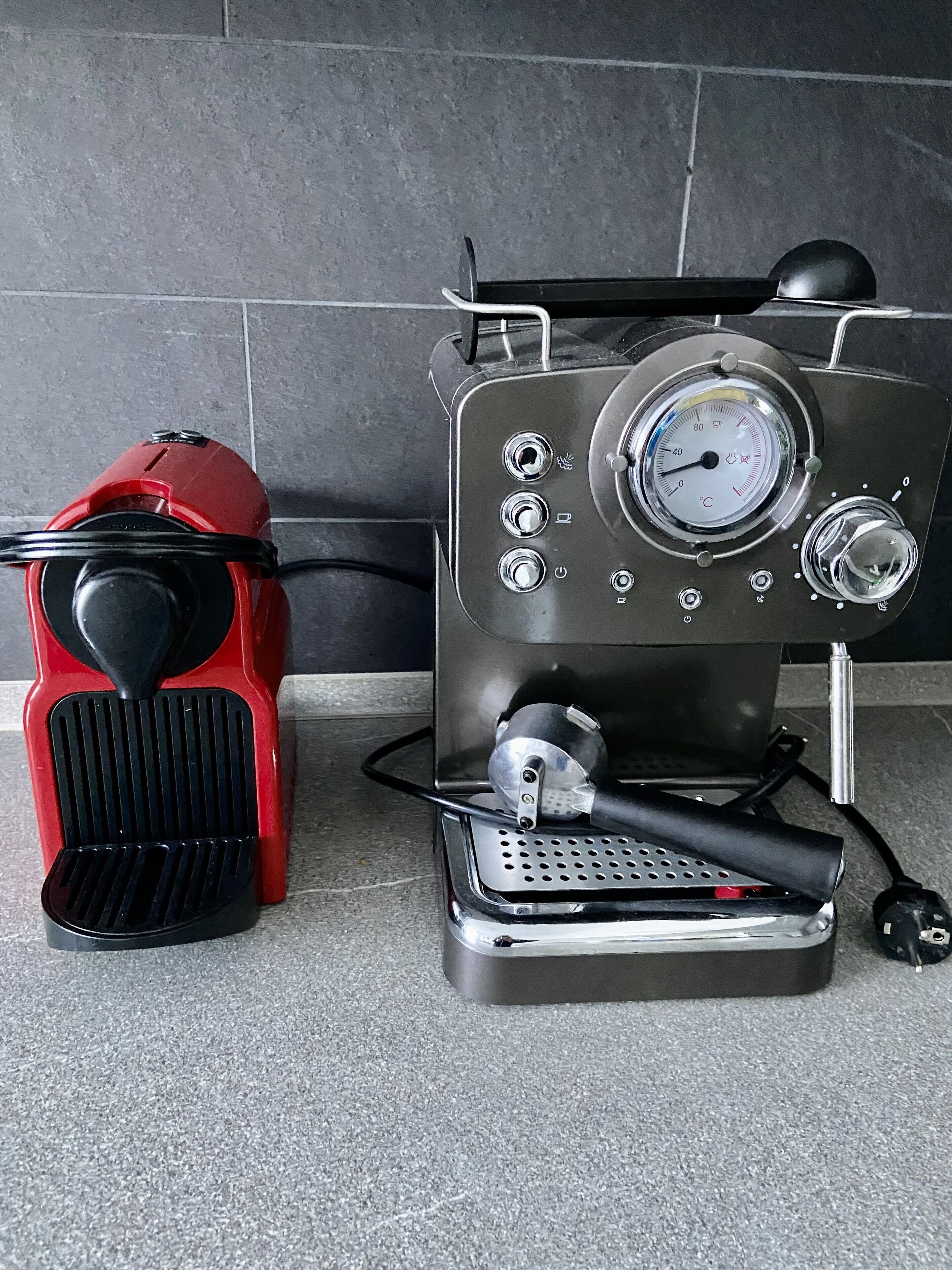 En kaffemaskine med digitalt display og rød kværn, stående på en flisetæller.