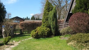 Een tuin met een pad dat naar een gebouw met een schuin dak leidt.