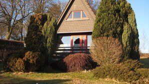 Een huis met een puntig dak, een klein terras en een raam.
