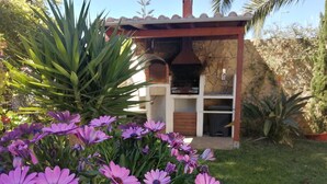 A garden with purple flowers and a stone wall. - Apartment m. Pool u. Sea view, about 500m to the beach in Sesimbra for max. 4 pers (Sesimbra)