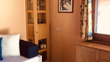 Una habitación acogedora con un armario de madera, un sofá blanco y un cuadro en la pared.