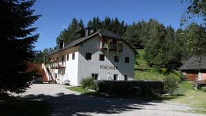 A two-story building with the name "PIRCHNER" on the side, surrounded by greenery and a clear sky. - New and fully furnished apartment! Calm and relaxation guaranteed! (St. Lorenzen)