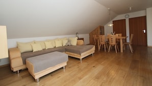 A modern living room with a sectional sofa, a small table, and a dining area with chairs. - New and fully furnished apartment! Calm and relaxation guaranteed! (St. Lorenzen)