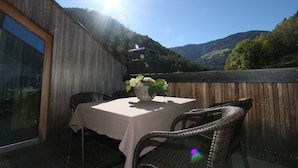 A patio with a table and chairs, a wicker basket with flowers, and a view of a mountainous landscape. - New and fully furnished apartment! Calm and relaxation guaranteed! (St. Lorenzen)
