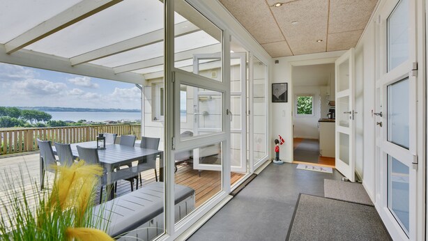 A modern interior with a balcony overlooking a scenic view, a dining area, and a kitchen.