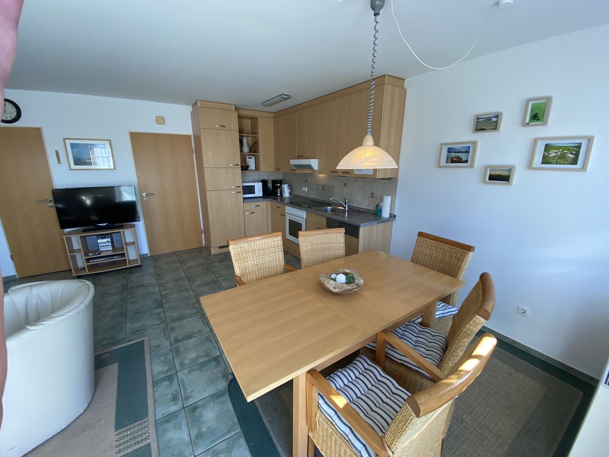 A compact living space with a dining area, kitchenette, and a television.