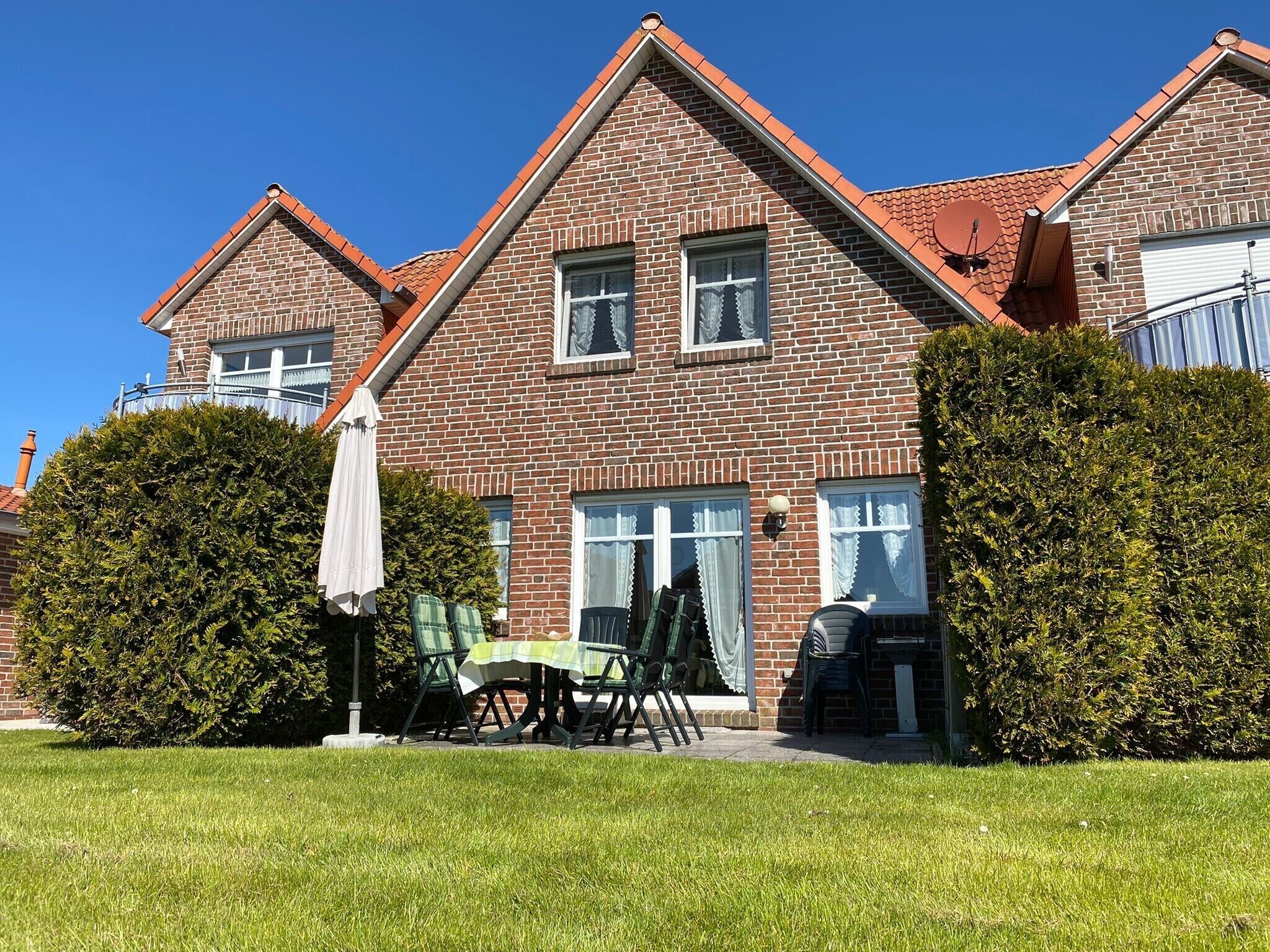 Een tweelaags bakstenen huis met een verzorgd gazon en een terras.