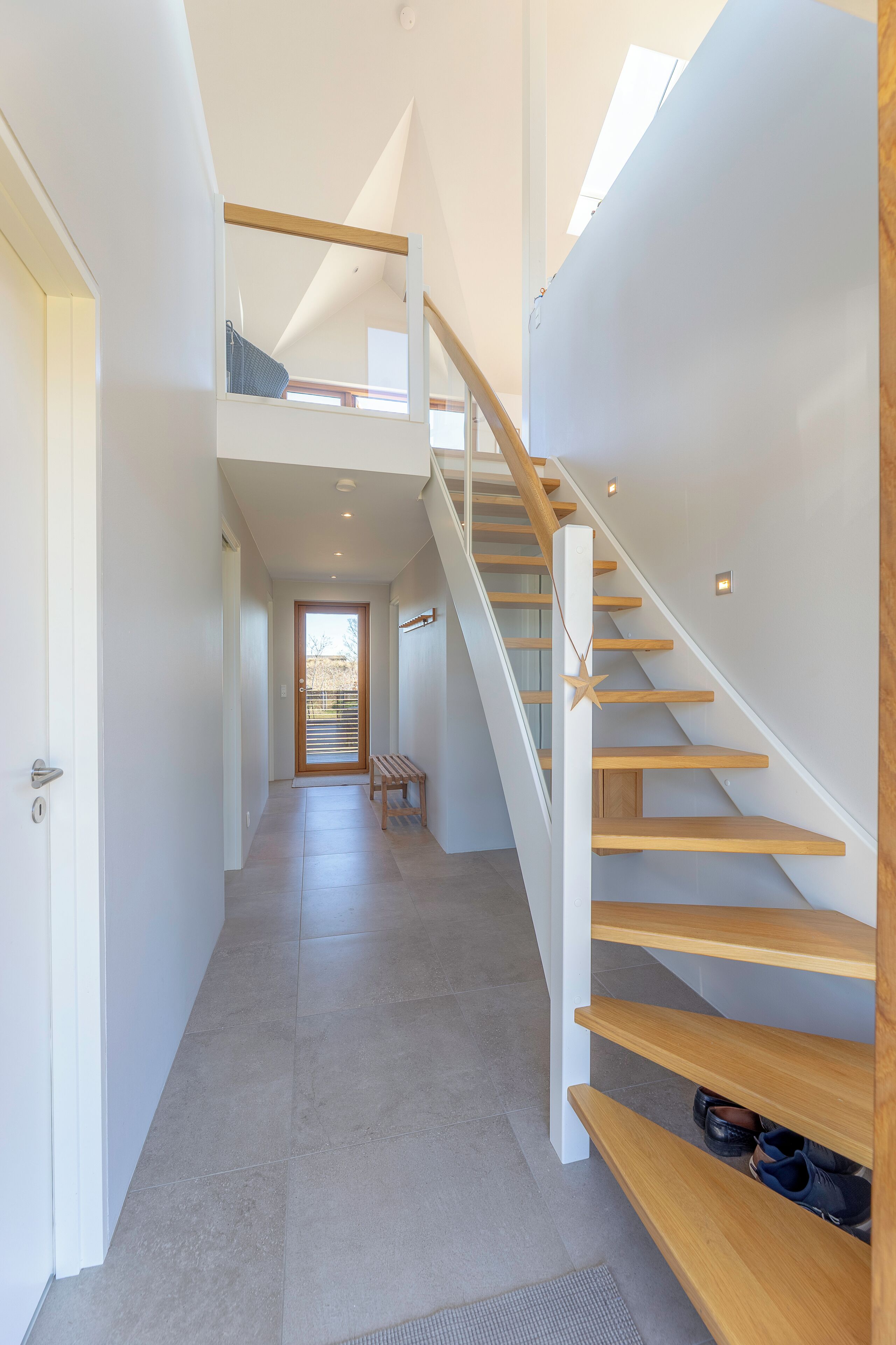 Un interior modern amb una escala, una banca i una porta que condueix a una altra habitació.