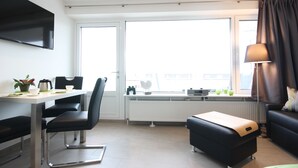 Un salon moderne comprenant un coin repas, de grandes fenêtres, un téléviseur à écran plat et un canapé.