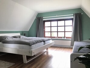 A bedroom with a bed, a window with curtains, a radiator, and a plant. - Holiday on the "Eulenhof" directly on the Este in the old country (Jork)