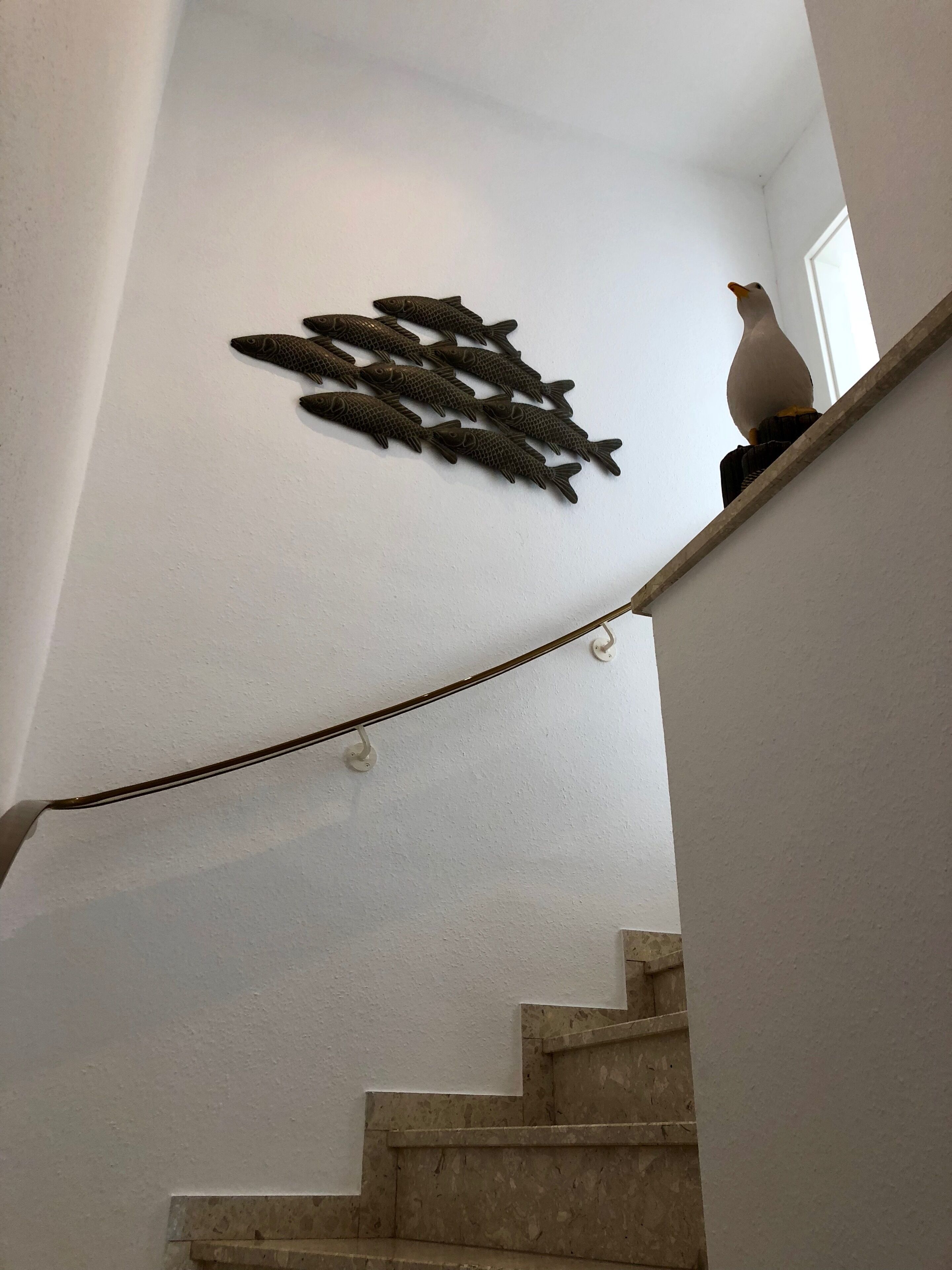 A staircase with a wall-mounted fish decoration and a seagull figurine.
