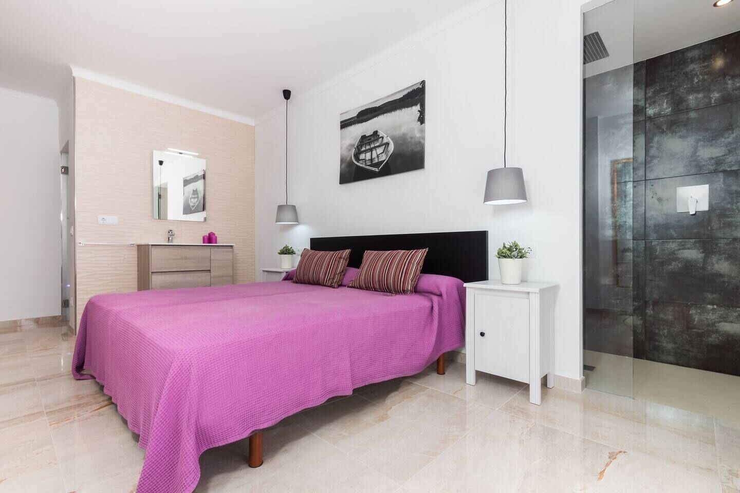 A modern bedroom with a bed, bedside tables, a mirror, and a large window.