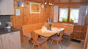 A wooden-paneled room with a dining table, chairs, a clock, and a window with curtains. - Freiburg, Southern Black Forest, Schauinsland Hofsgrund, farm houses, (Oberried)