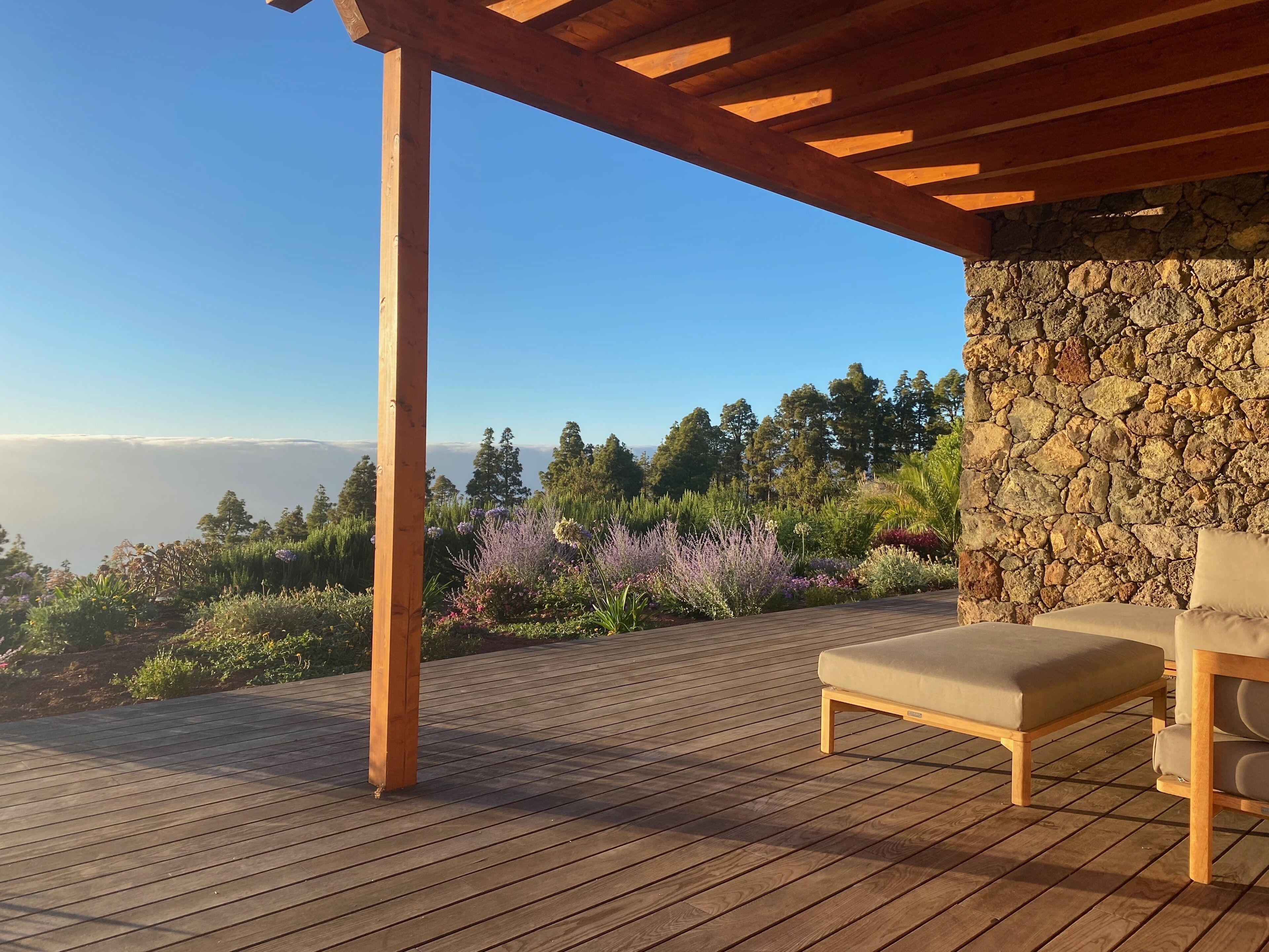 Une terrasse en bois avec un muret en pierre et un banc.