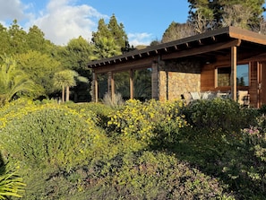 A modern house with a stone facade, large windows, and a covered patio area.