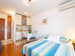 A bedroom with a bed, a small table, and a kitchenette area. - Studio with air conditioning (Pula)
