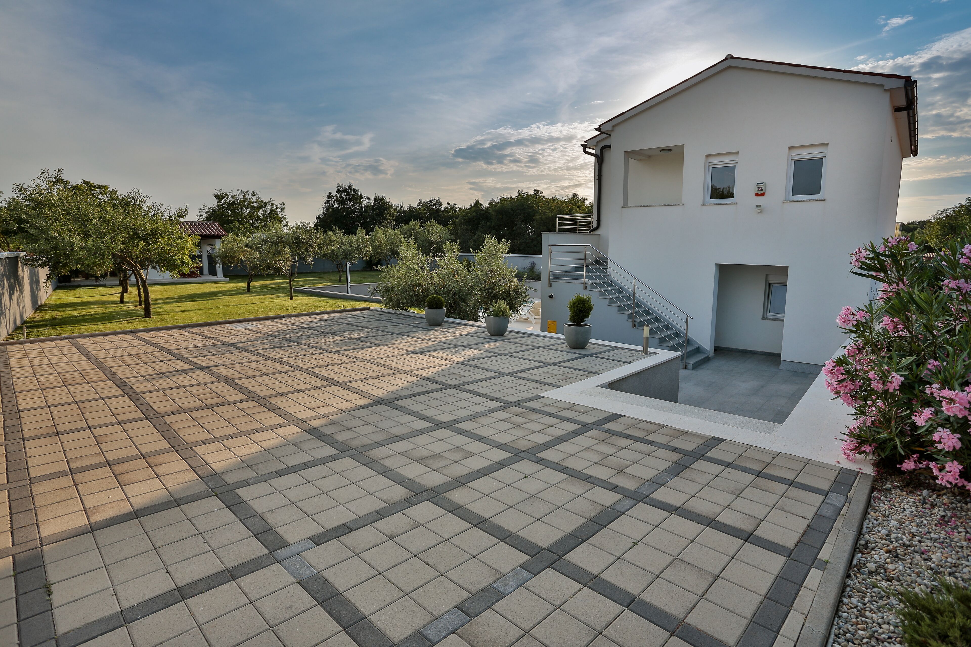A modern building with a tiled patio, a staircase, and a small garden area.