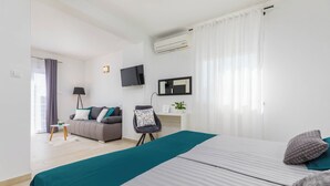 Ein modernes Hotelzimmer mit einem großen Bett, einer Couch, einem Schreibtisch und einem Fernseher.