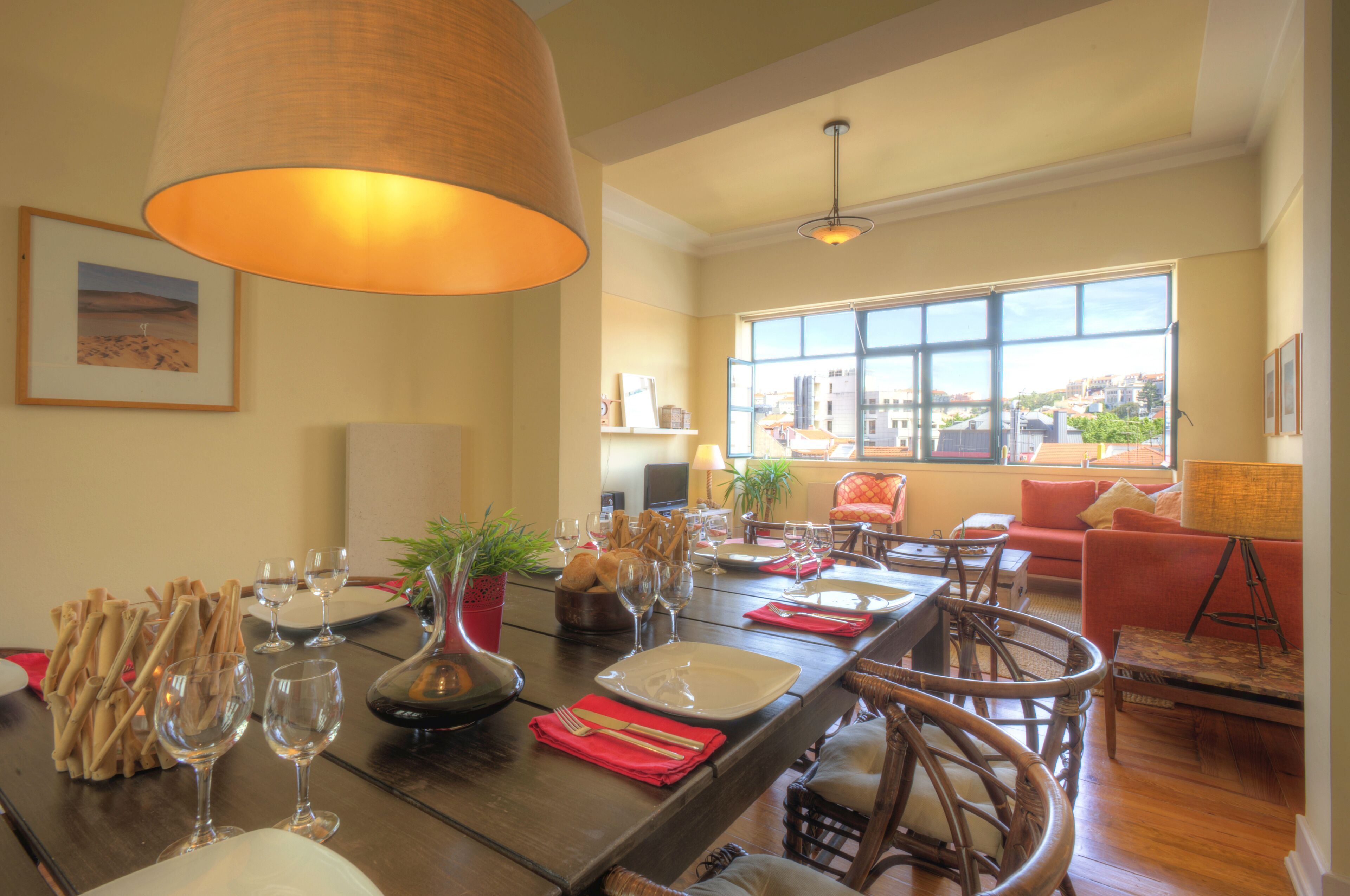 Un coin repas avec une table en bois dressée pour quatre personnes, entourée de chaises en osier.