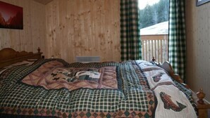 Una habitación de cabaña de madera con una cama grande, una ventana con cortinas y vistas a un paisaje nevado.