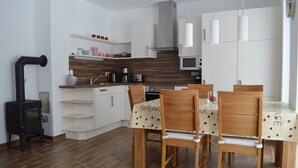 A modern kitchen with white cabinets, a black stove, and a dining area with wooden chairs and a table. - Beautiful apartment! 250 m to the Baltic Sea beach. Standing vacation, short trip or mobile working. (Börgerende-Rethwisch)