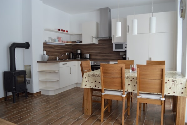 A modern kitchen with white cabinets, a black stove, and a dining area with wooden chairs and a table.
