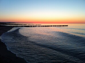 A pier extending into calm waters at sunset.