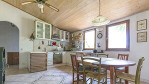 A kitchen with wooden cabinets, a dining table with chairs, and a ceiling fan.