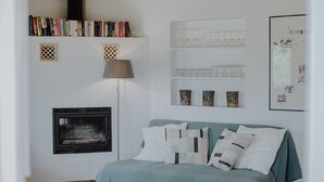 A cozy living room with a wooden ceiling, a bookshelf with books, a fireplace, a bed with pillows, and a coffee table. - Small but nice finca with great views and pool near Cala Ratjada (Capdepera)