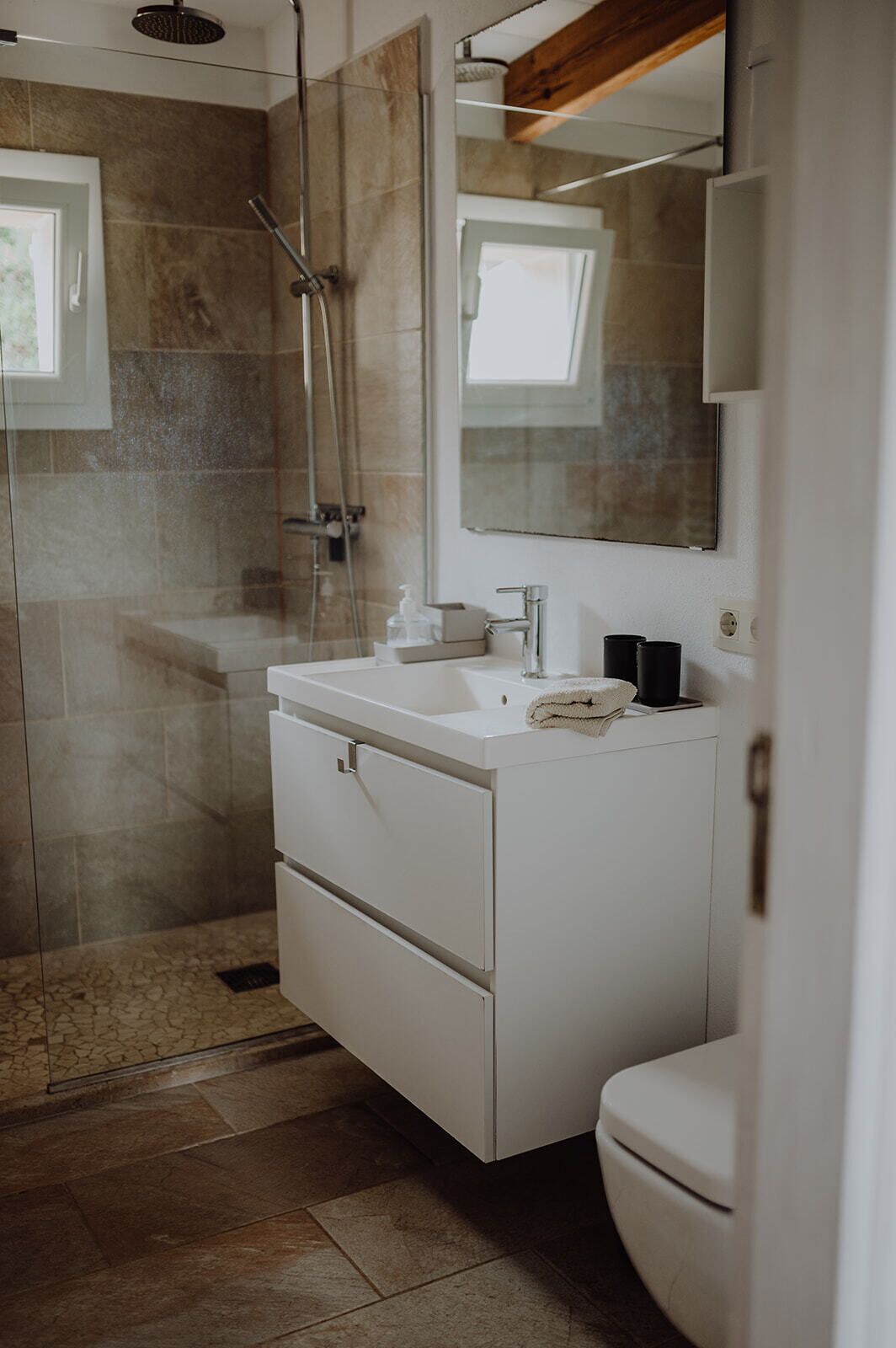 A modern bathroom with a glass-enclosed shower, a white vanity with a mirror, and a toilet.