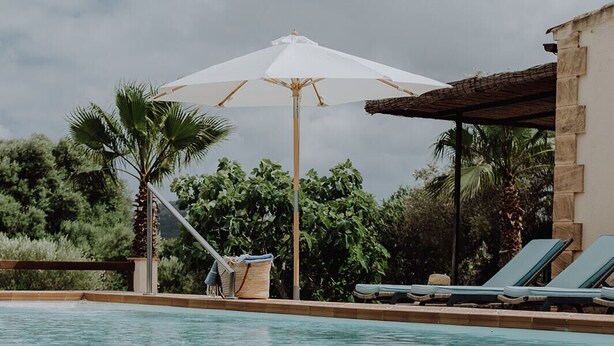 A swimming pool with lounge chairs and umbrellas. - Small but nice finca with great views and pool near Cala Ratjada (Capdepera)
