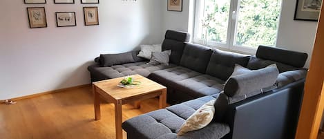 A modern living room with a sectional sofa, a wooden coffee table, and framed artwork on the walls.