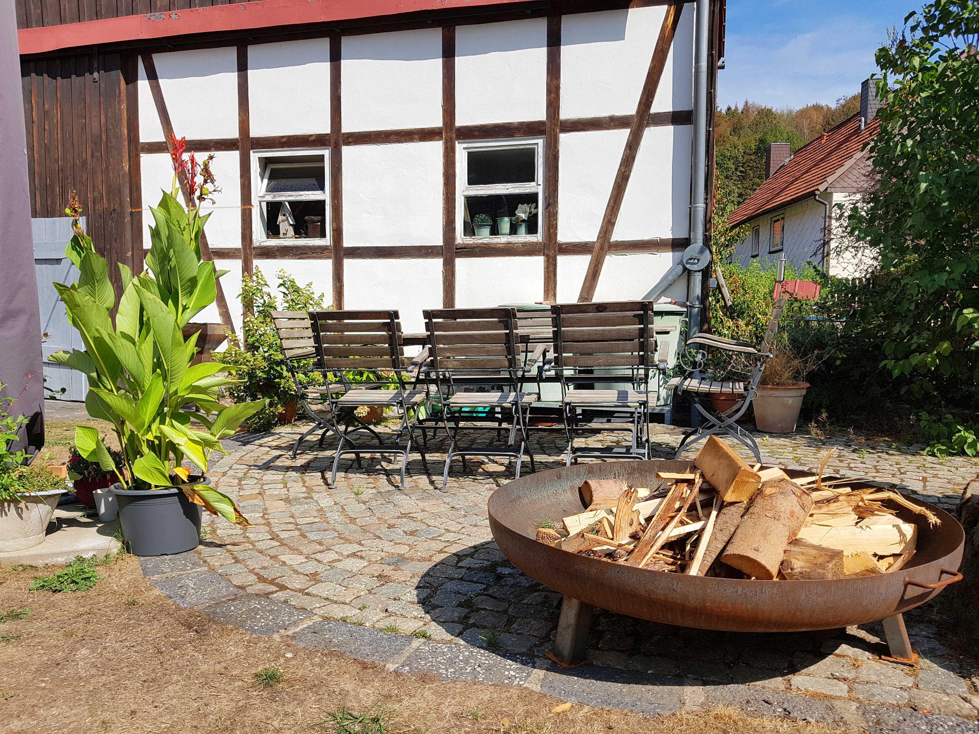 A courtyard with a fire pit, wooden benches, and potted plants.
