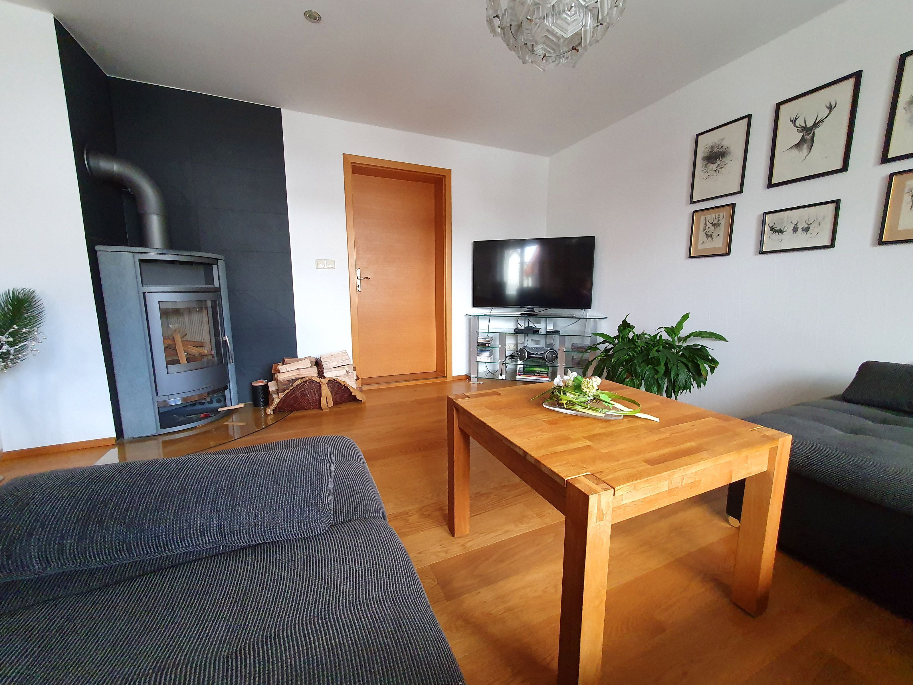 A living room with a sofa, a wooden coffee table, a TV, and framed pictures on the wall.