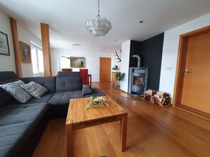 Una sala de estar moderna con sofá, una mesa de centro de madera, chimenea y un comedor con una silla roja.