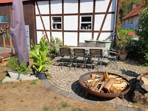 Um pátio com lareira, área de estar externa e plantas em vasos.