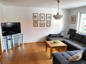 Una sala de estar con televisor, sofá, mesa de centro y una obra de arte en la pared.