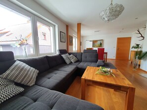 A modern living room with a sectional sofa, a wooden coffee table, and a chandelier.