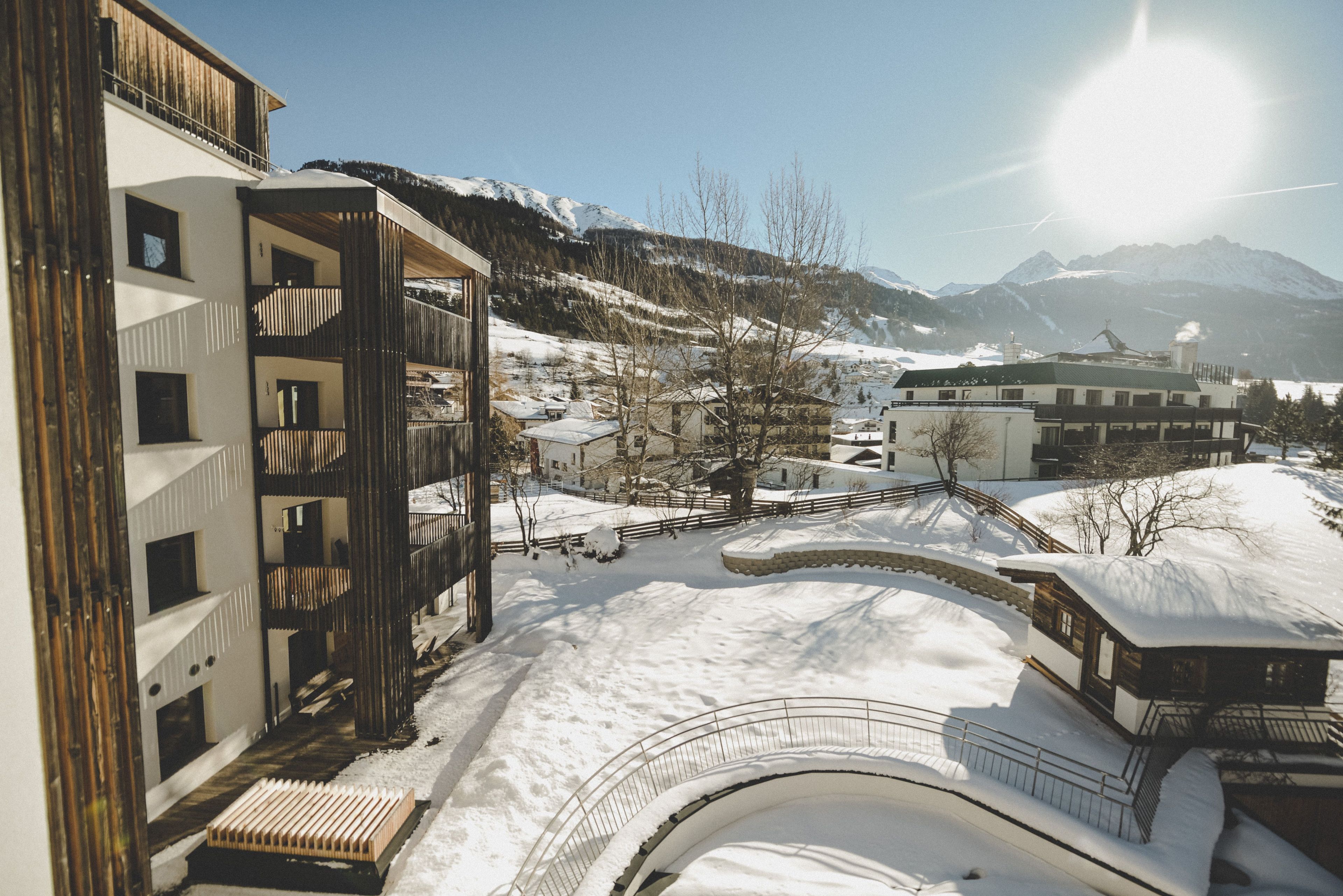 Un bâtiment moderne doté de nombreux balcons, un paysage enneigé et des montagnes en arrière-plan.