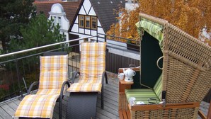 A deck with wicker chairs and a small table with a teapot and cup. - Comfortable 4-star roof terrace apartment, quiet and central, 4 adults + 1 baby (Rostock)