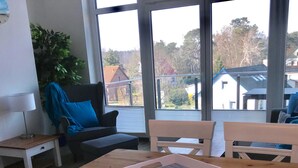 A dining area with a wooden table, white chairs, and a laptop on the table. - Upper deck 2.06, Germany (Glowe auf Rügen)