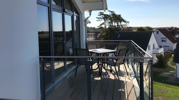A balcony with a table and chairs, large windows, and a view of the neighborhood. - Upper deck 2.06, Germany (Glowe auf Rügen)