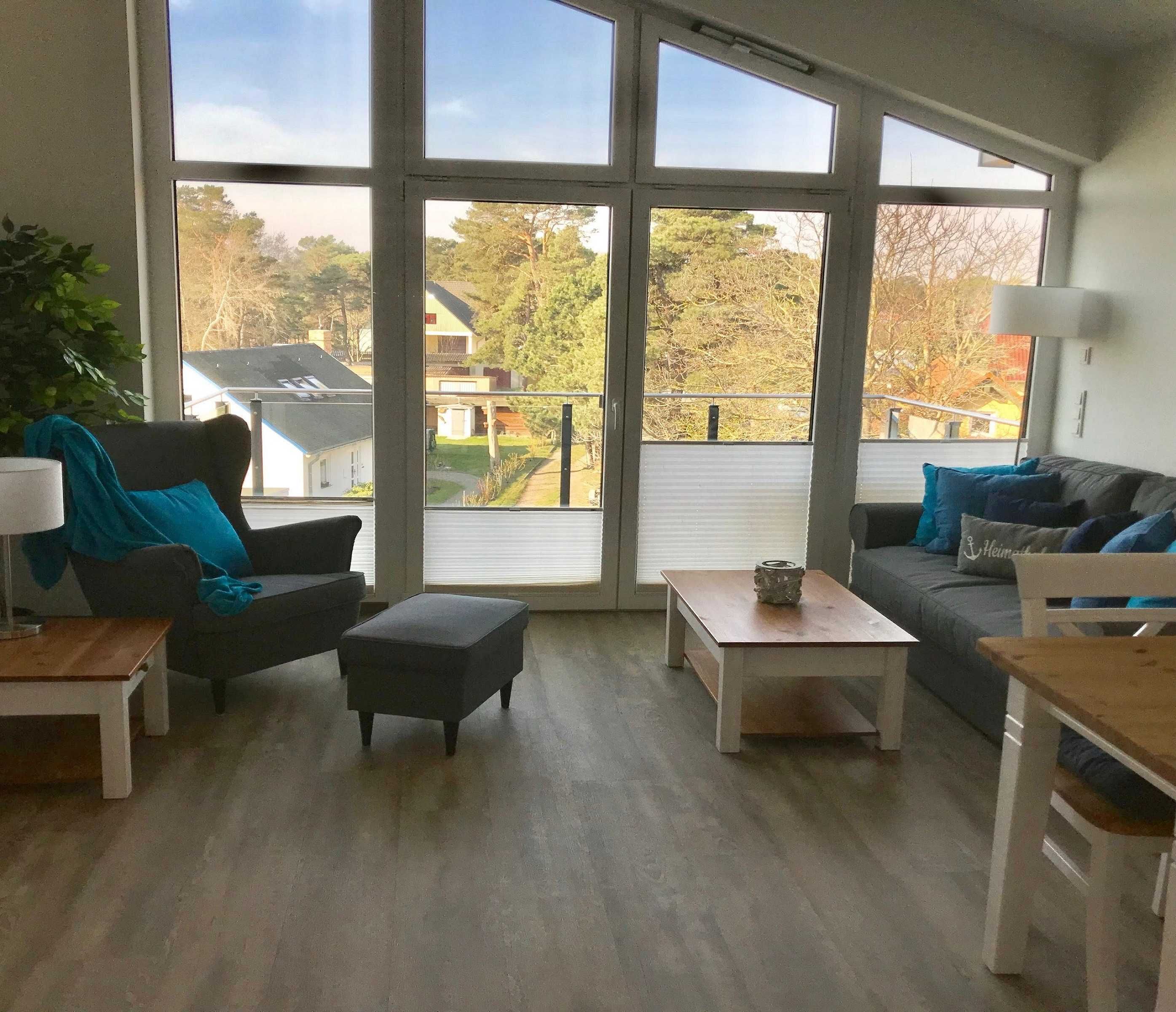 Un salon spacieux doté de grandes fenêtres, d’un canapé, d’une table basse et d’un fauteuil.
