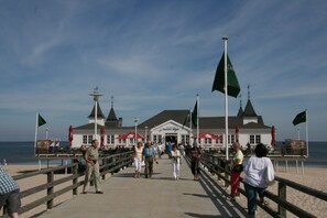 A pier with a building at the end, featuring a flag, a flagpole, and a view of the beach. - RESIDENZ-MEERESRAUSCHEN vacation apartment with sauna directly on the beach - pure relaxation (Heringsdorf)